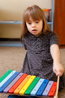 Front view girl with down syndrome playing with xylophone