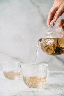 Person pouring tea cups marble background