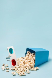 3d glasses with spilled popcorns blue background