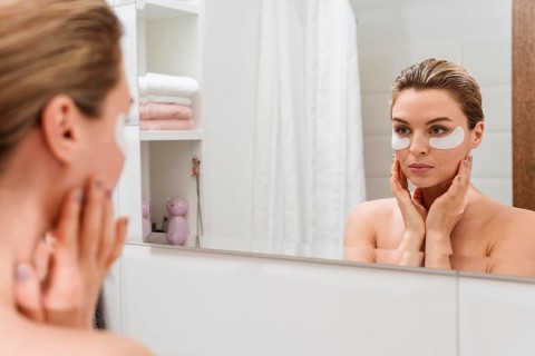 Woman using reducing dark circles patches mirror