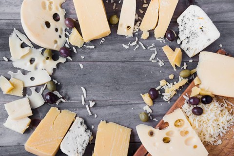 Circular frame made with different type cheese olives wooden table