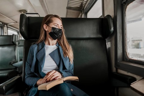 Passenger train wearing medical mask looking out window
