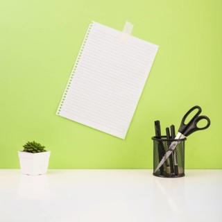 Pens scissors holder near paper stucked green wall