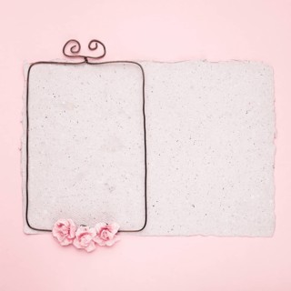 Rectangular wire frame decorated with roses paper against pink background