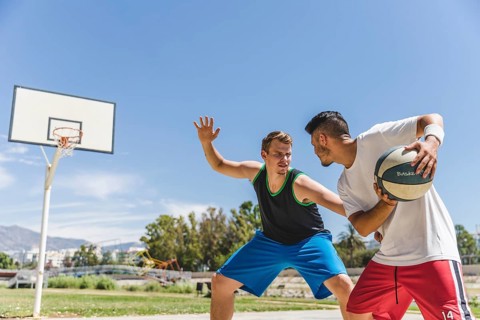 Young male player playing with basketball player