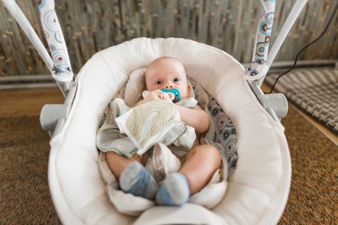 Cute baby with pacifier lying baby carriage home
