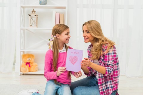 Daughter giving greeting card mother