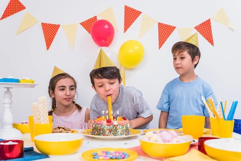 Two friends looking boy blowing out candles birthday cake