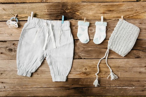 Baby s pant socks headwear pacifier hanging clothesline with clothespins against wooden wall