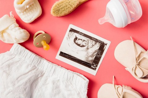 Baby clothing socks brush pacifier pair shoes milk bottle ultrasound picture peach background