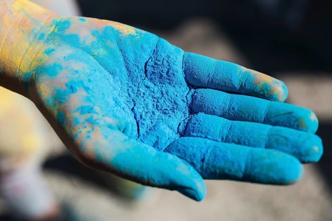 Close up person s hand holding blue holi color