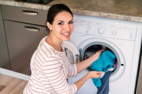 Lady putting clothes washing machine
