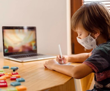 Boy wearing medical mask attending virtual school