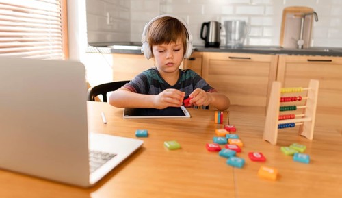 Child wearing headphones attending virtual classes