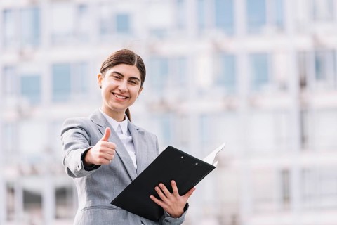 Modern businesswoman with clipboard outdoors