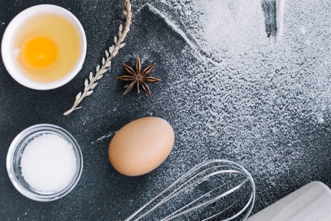 Elevated view sugar egg grains star anise whisk flour kitchen counter