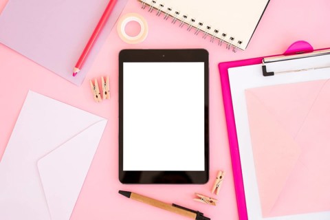 Top view tablet with pink stationery