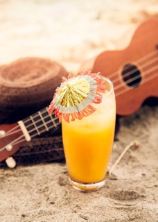 Glass with drink ukulele straw hat placed sand