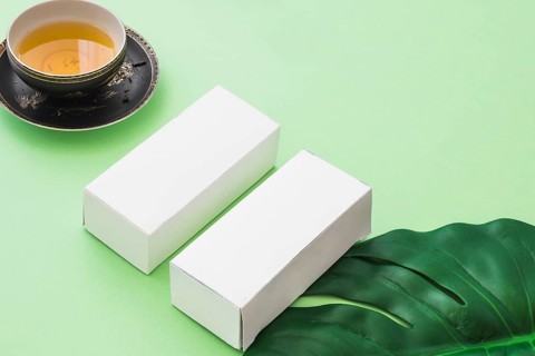 Herbal tea cup two white boxes with leaf green background