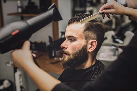 Crop woman drying hair man barbershop
