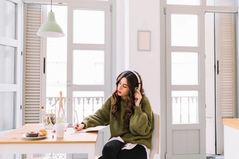 Focused woman drawing listening music