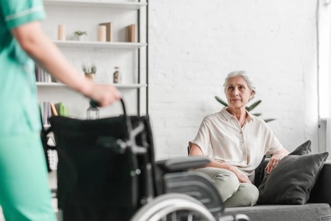 Nurse holding wheelchair front senior female patient