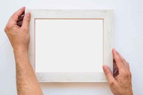 Man s hand placing white picture frame wall
