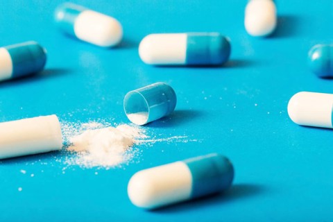 Broken capsule with white powder blue background