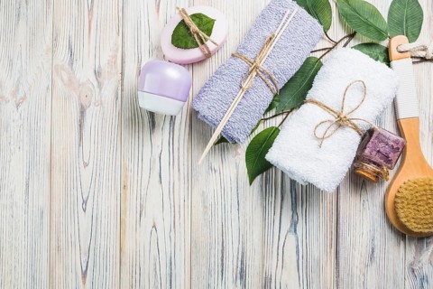Towels scrub bottle moisturizing cream leaves brush soap wooden plank