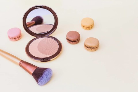 Blusher with macaroon makeup brush beige background