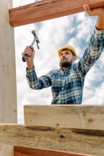 Construction worker with hammer hard hat building roof house