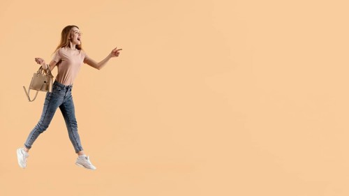 Young female model with hand bag jumping