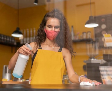 Barista wearing medical mask while cleaning coffee shop