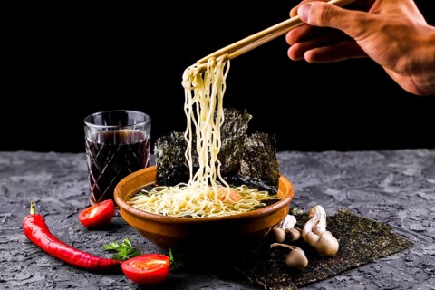 Hand with chopsticks noodles soup