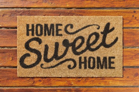 Overhead of home sweet home doormat on the wood plank porch
