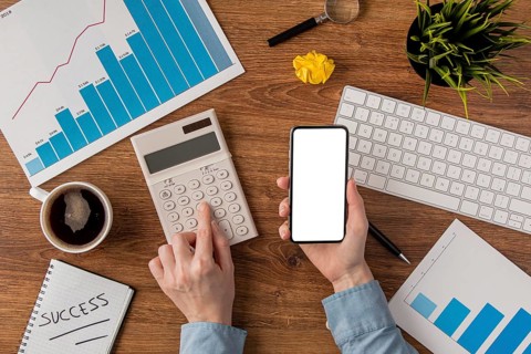 Top view office desk with growth chart hands using calculator