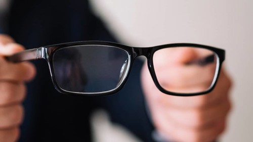 Man holding pair glasses with black frame
