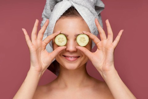 Beautiful woman using cucumber slices eyes