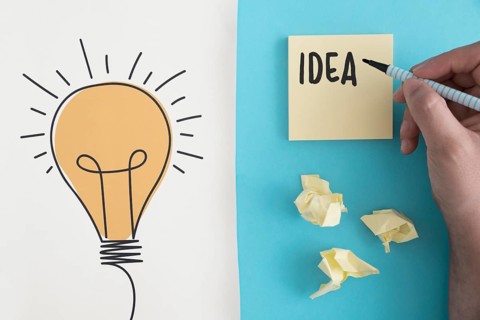Idea text written with felt pen crumpled ball paper with hand drawn light bulb