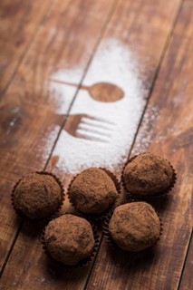 Homemade chocolate truffle candies with cocoa powder near spoon fork shape sugar powder