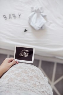 Mother holding x ray fetus close her belly