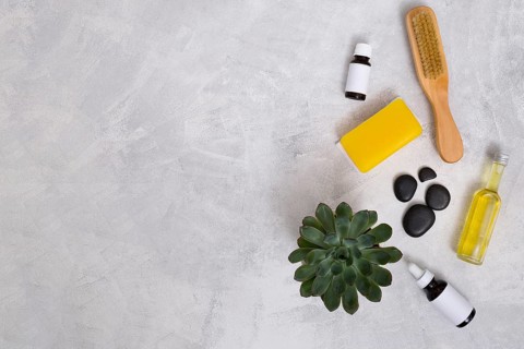Wooden brush la stone essential oil bottles yellow soap cactus plant concrete backdrop with space writing text