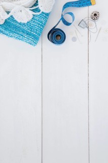 Crochet knitted fabric measuring tape pushpin thimble thread button wooden table