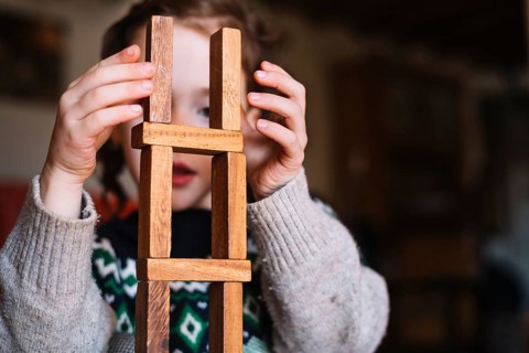 Close up girl balancing stacked wooden blocks
