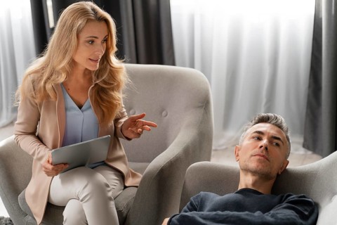 Woman therapist talking man laying couch
