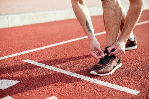 Low section male athlete start line tying his shoelace running track