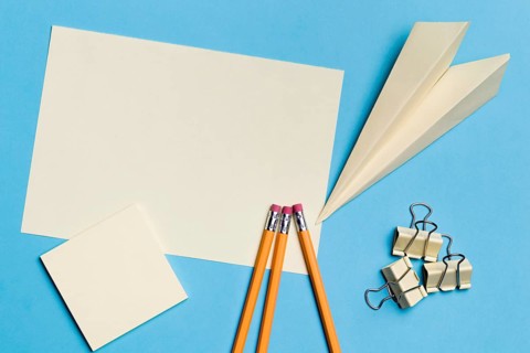 Top view paper plane with pencils desk