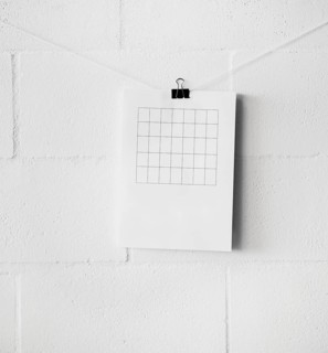 Am empty table paper attach string with paperclip against white wall