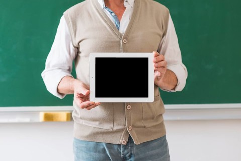Professor holding tablet with blank space classroom