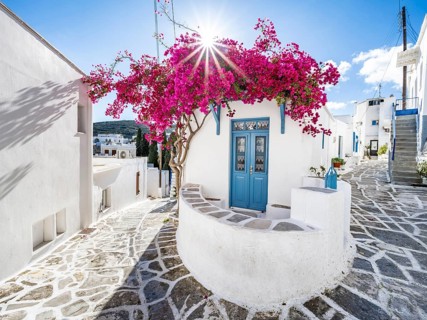 White Cycladic house with blue door and pink bougainvillea